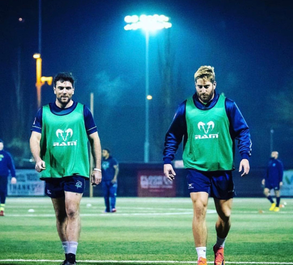 Giocatori di rugby che indossano pettorine da allenamento verdi RAM sotto i riflettori