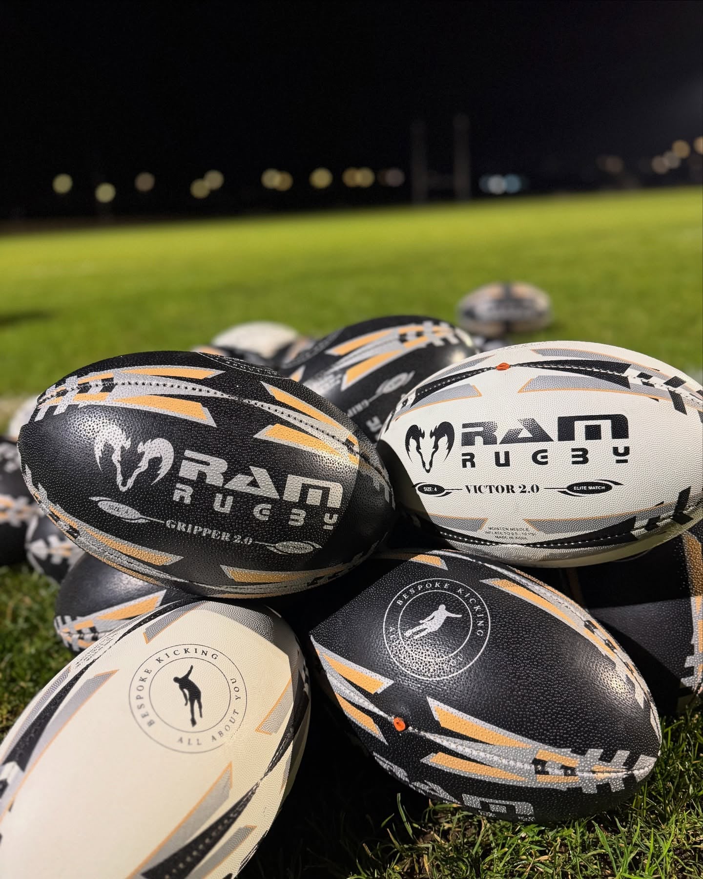 Stack of RAM Rugby balls on a grass field at night